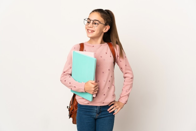 Piccola donna dell'allievo sopra la parete isolata che posa con le braccia all'anca e sorridere