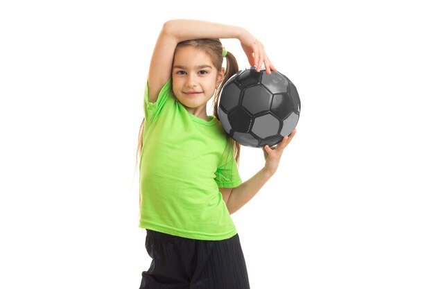 Piccola donna sveglia con un pallone da calcio nelle mani isolate su bianco