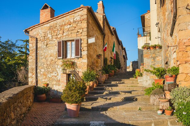 Piccola e antica cittadina mediterranea stradina a Pienza con luce solare e fiori Toscana Italia Europa