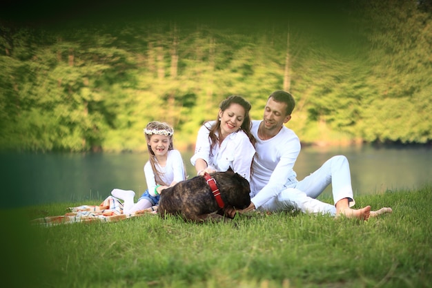 ,piccola figlia e il loro cane su un picnic in riva al fiume.la foto ha uno spazio per il tuo testo