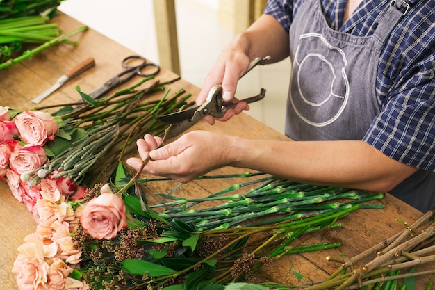 Piccola impresa. Primo piano maschio delle mani del fiorista, tagli rosa per bouquet nel negozio di fiori. Consegna fiori, creazione ordine