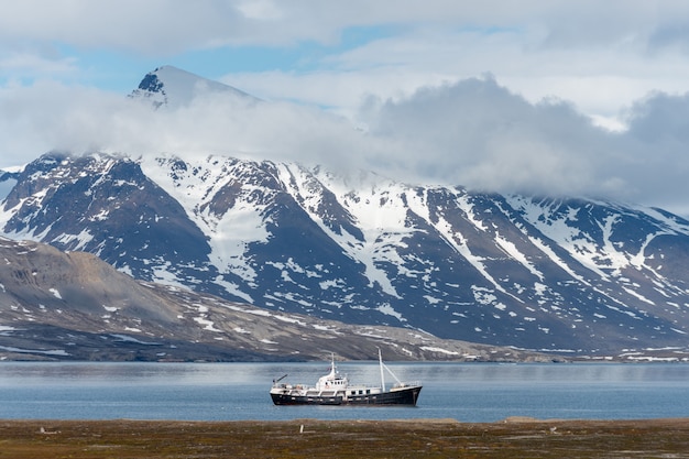 Piccola nave a vela con bella montagna innevata alle Svalbard