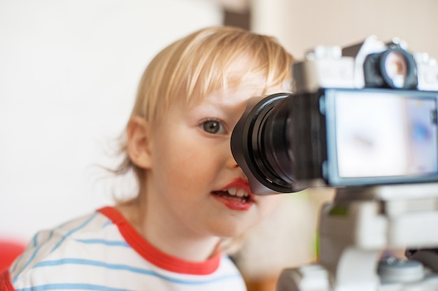 Piccola neonata bionda divertente esamina la macchina fotografica. Imparare a posare per la macchina fotografica come l&#39;am