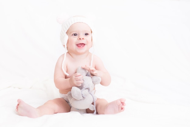 Piccola neonata sveglia con il suo giocattolo di elefante di peluche preferito che sorride mostrando i suoi primi denti bianchi.