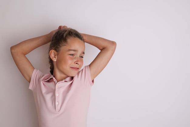 Piccola ragazza adolescente emotiva in camicia rosa 11 12 anni su uno sfondo bianco isolato Ritratto in studio per bambini Posizionare il testo per copiare lo spazio per l39iscrizione pubblicità merci per bambini