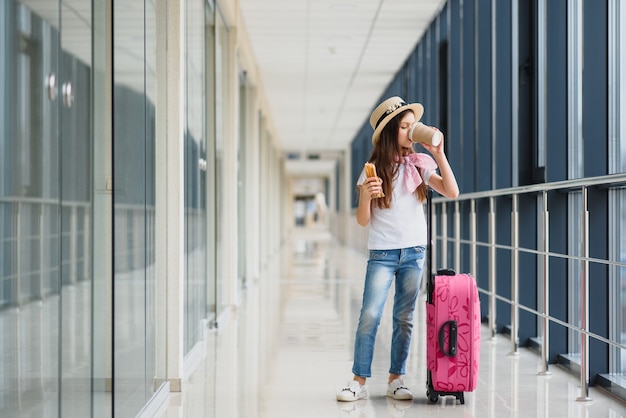 Piccola ragazza adorabile all'aeroporto con un bagaglio