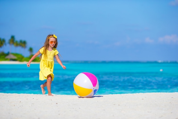 Piccola ragazza adorabile che gioca sulla spiaggia con la palla