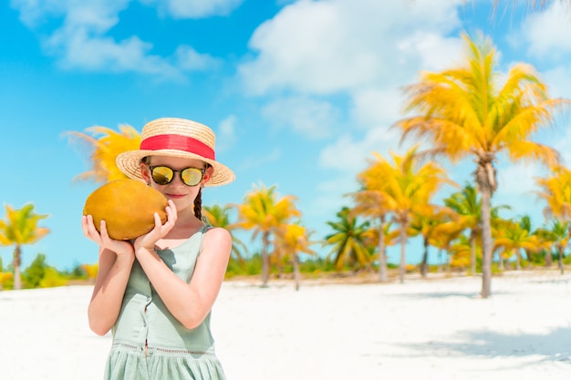 Piccola ragazza adorabile con grande noce di cocco sulla spiaggia