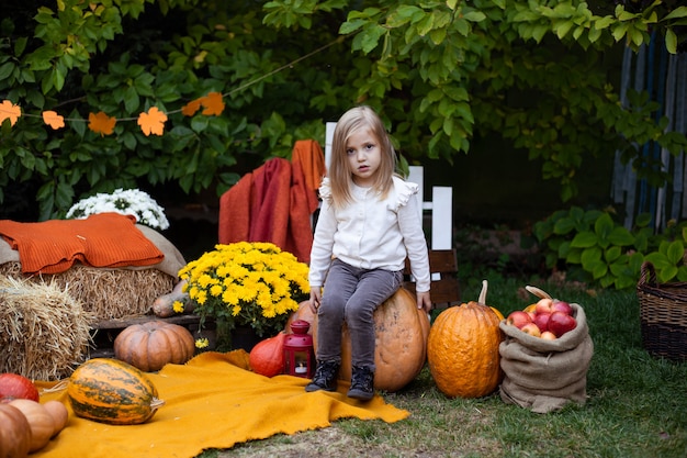 Piccola ragazza adorabile con la zucca all'aperto