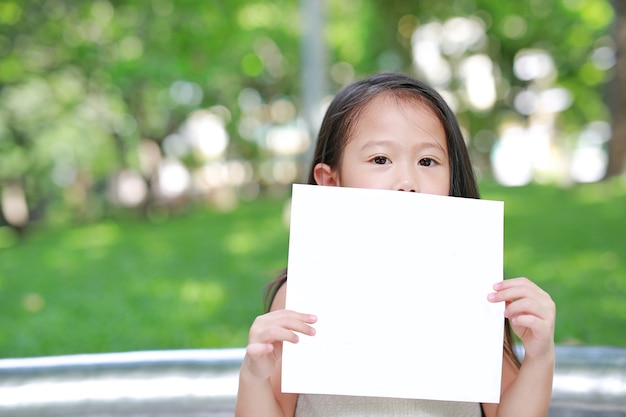 Piccola ragazza adorabile del bambino asiatico che sostiene un Libro Bianco in bianco.