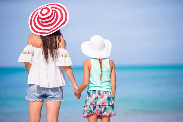 Piccola ragazza adorabile e giovane madre alla spiaggia tropicale