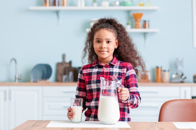 Piccola ragazza afro-americana con latte in cucina