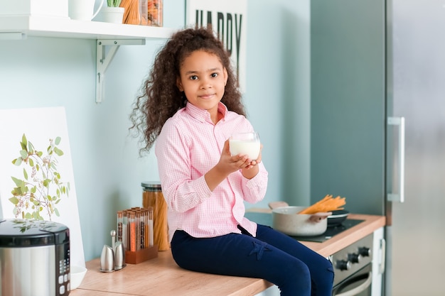 Piccola ragazza afro-americana con latte in cucina