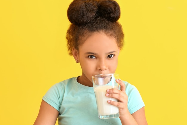 Piccola ragazza afro-americana con latte sul colore