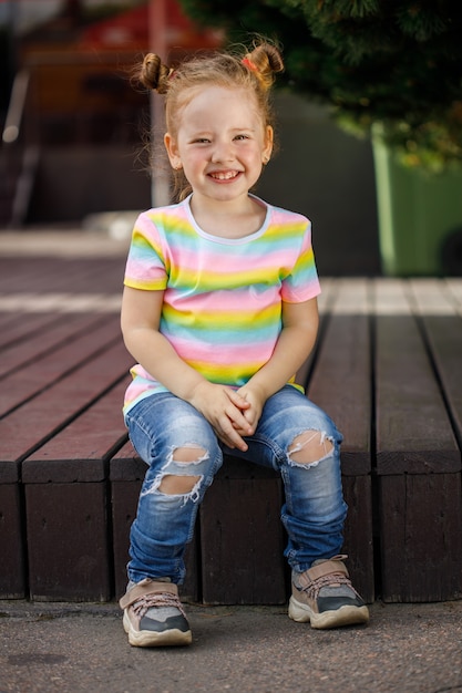 Piccola ragazza alla moda in jeans e una maglietta colorata