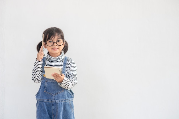 Piccola ragazza asiatica carina con gli occhiali e pensa