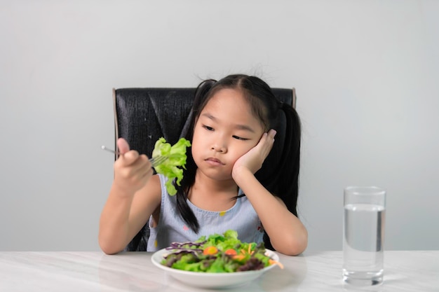 Piccola ragazza asiatica carina si rifiuta di mangiare verdure sane Nutrizione abitudini alimentari sane per i bambini concettoI bambini non amano mangiare verdure