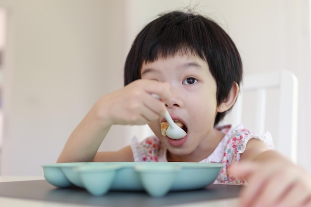 Piccola ragazza asiatica che fa colazione