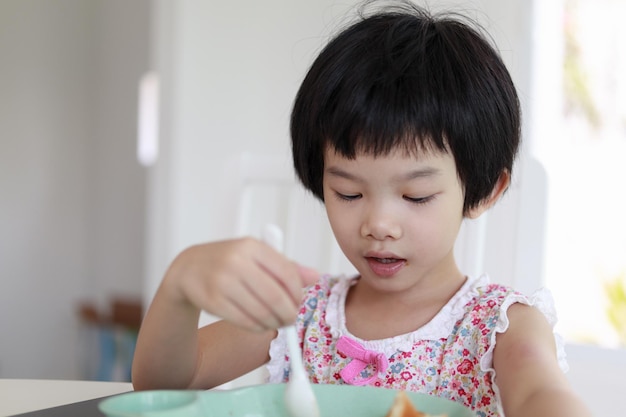 Piccola ragazza asiatica che fa colazione