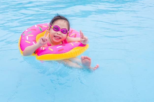 Piccola ragazza asiatica che nuota con l&#39;anello in piscina