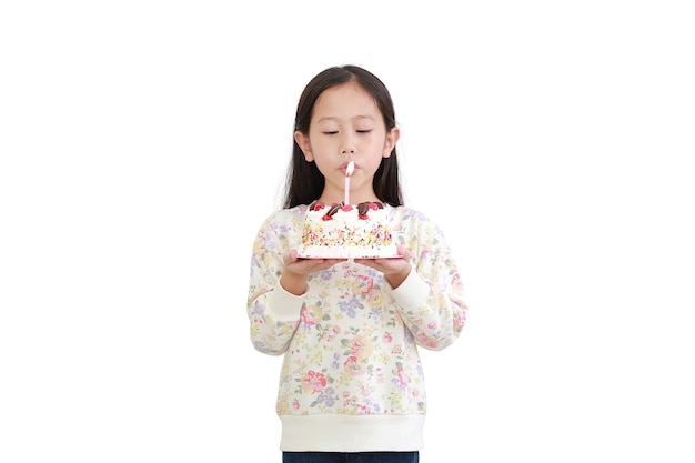 Piccola ragazza asiatica che soffia candela sulla torta di buon compleanno isolata