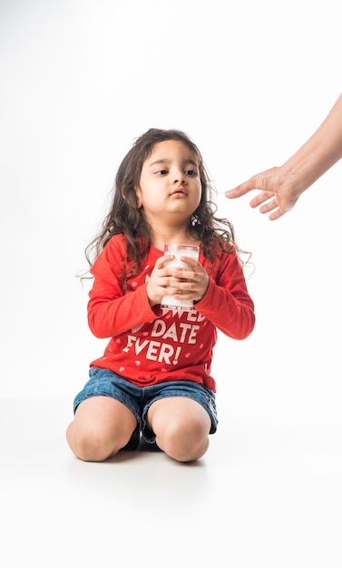 Piccola ragazza asiatica indiana carina con in mano un bicchiere pieno di latte - concetto di alimentazione sana