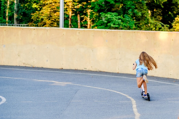 Piccola ragazza bionda che guida sul motorino