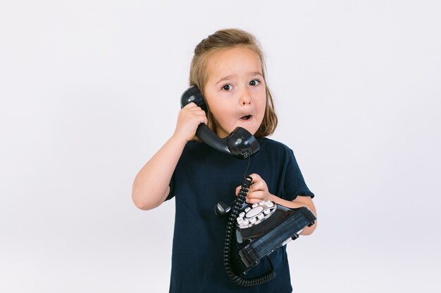 Piccola ragazza bionda che parla sul suo telefono retrò