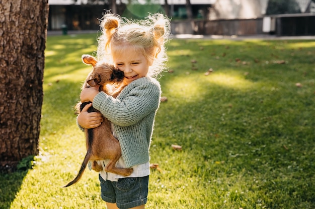 Piccola ragazza bionda con un cucciolo all'aperto