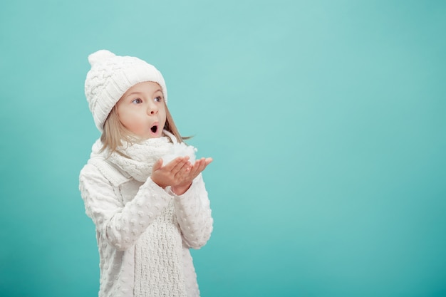 Piccola ragazza bionda in un cappello bianco e sciarpa