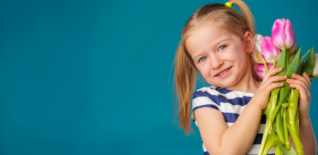 Piccola ragazza bionda sorridente con il mazzo dei tulipani