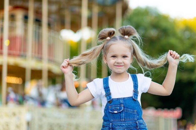 Piccola ragazza bionda sveglia in un parco di divertimenti