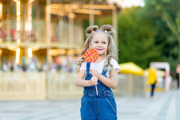 Piccola ragazza bionda sveglia in un parco di divertimenti