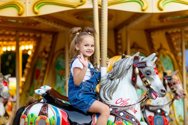 Piccola ragazza bionda sveglia in un parco di divertimenti