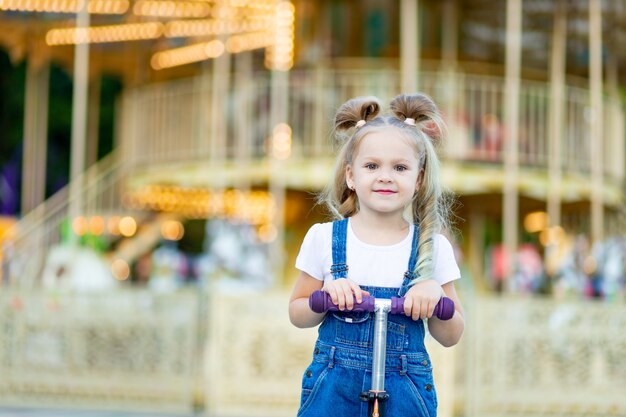 Piccola ragazza bionda sveglia in un parco di divertimenti