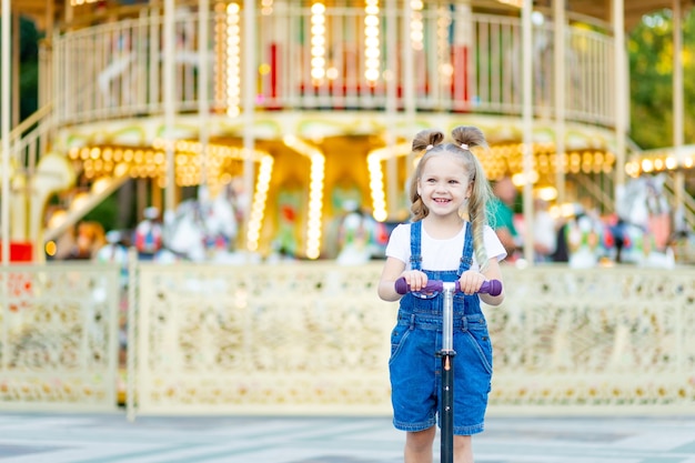 Piccola ragazza bionda sveglia nel parco di divertimenti