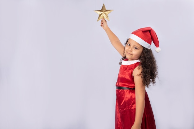 piccola ragazza brasiliana vestita con costume natalizio tenendo la stella d'oro