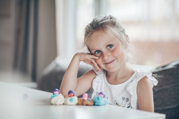 Piccola ragazza carina bambino in età prescolare che gioca giochi educativi con figure di plastilina che si preparano per la scuola