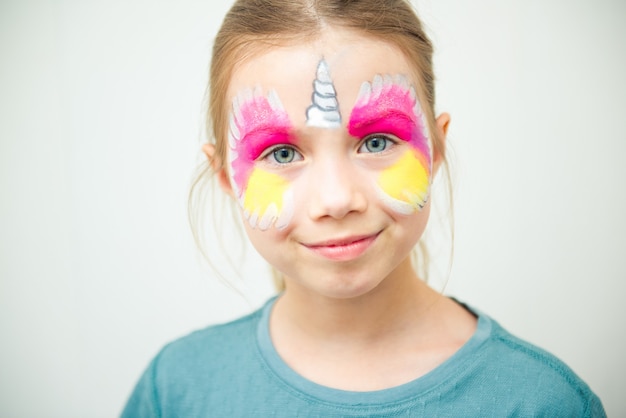 Piccola ragazza carina caucasica con pittura del viso di unicorno