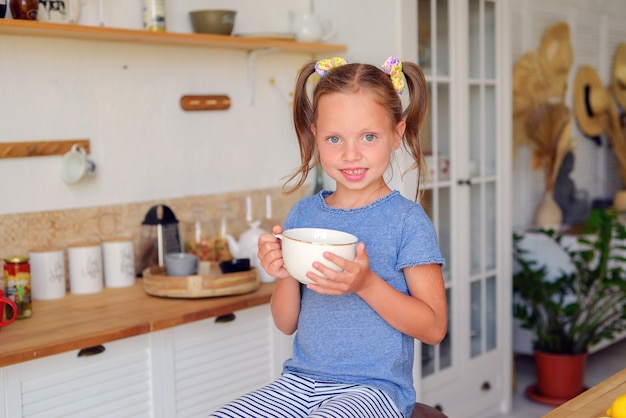 piccola ragazza carina che beve tè al limone in cucina infanzia felice