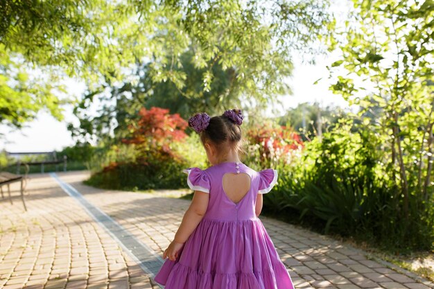 Piccola ragazza carina che cammina nel parco estivo all'aperto Concetto di infanzia