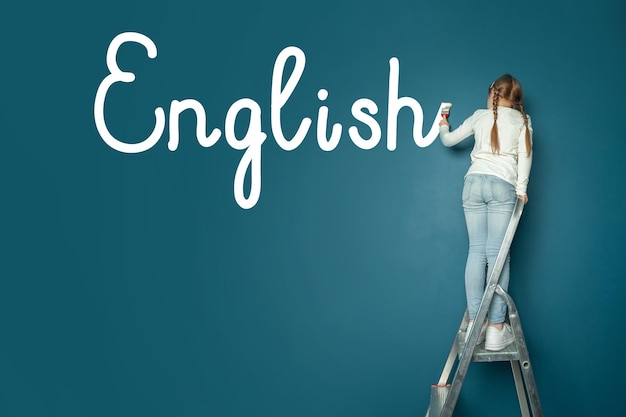 Piccola ragazza carina che scrive inglese Imparare il concetto della lingua inglese