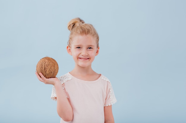 Piccola ragazza carina con una noce di cocco fresca