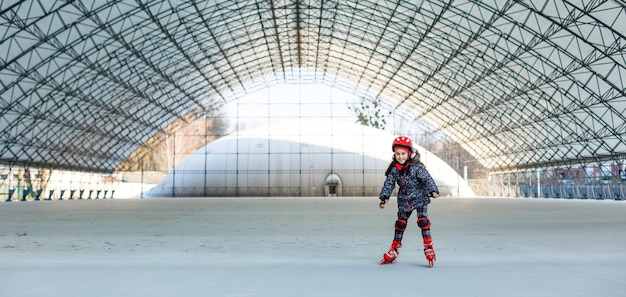 piccola ragazza carina e felice che pattina in un grande hangar