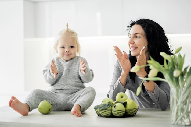 Piccola ragazza carina figlia bambini bionda e mamma bruna giovane famiglia gioca sorridente