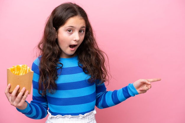 Piccola ragazza caucasica che celebra un compleanno isolato su sfondo bianco sorpresa e puntando il dito di lato