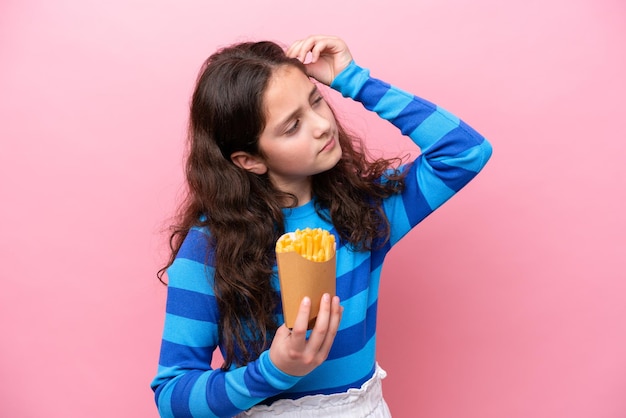 Piccola ragazza caucasica che festeggia un compleanno isolata su sfondo bianco con dubbi e con un'espressione facciale confusa