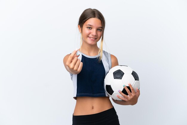 Piccola ragazza caucasica che gioca a calcio isolata su sfondo bianco facendo un gesto imminente