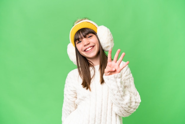 Piccola ragazza caucasica che indossa manicotti invernali su sfondo isolato felice e contando quattro con le dita