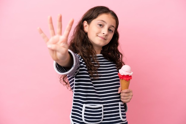 Piccola ragazza caucasica che tiene un gelato isolato su sfondo rosa felice e conta quattro con le dita